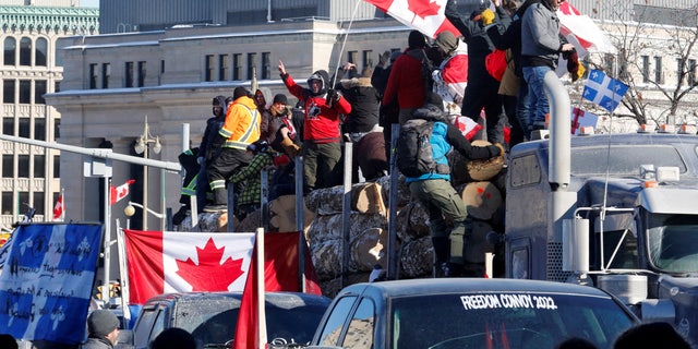 FOTO DE ARCHIVO: Los manifestantes se paran en un tráiler que transporta troncos mientras los camioneros y simpatizantes participan en un convoy para protestar por los mandatos de una vacuna contra el coronavirus (COVID-19) para los camioneros transfronterizos en Ottawa, Ontario, Canadá, el 29 de enero de 2022. REUTERS/PATRICK DOYLE/ARCHIVO Imagen
