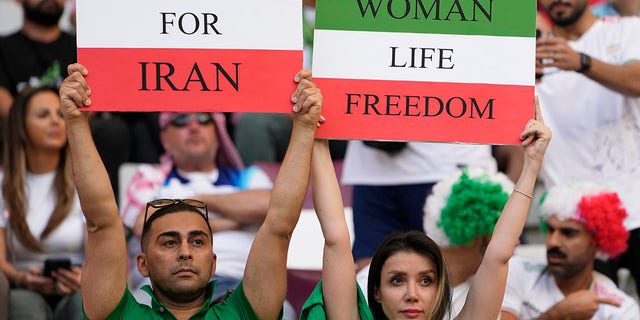 Los fanáticos del fútbol iraníes sostienen pancartas que dicen 