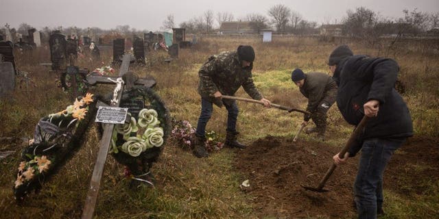 Residentes y funcionarios ucranianos exhuman el cuerpo de una niña de 16 años y otros siete hombres que fueron asesinados por las fuerzas rusas y enterrados en la ciudad de Pravdin, en las afueras de Kherson, el 29 de noviembre de 2022.
