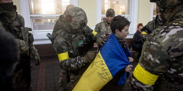 Un niño sostiene su bandera nacional ucraniana firmada por miembros del ejército ucraniano, el 19 de noviembre de 2022, en Kherson, Ucrania.