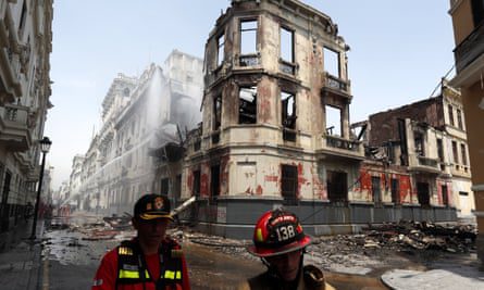Los bomberos trabajan afuera de una mansión histórica destruida por el fuego durante las protestas en el centro de Lima.