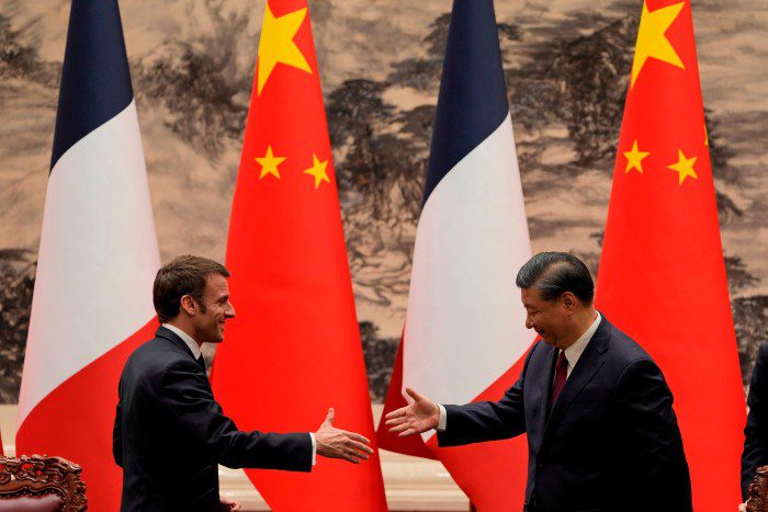 El presidente francés Emmanuel Macron le da la mano al presidente chino Xi Jinping