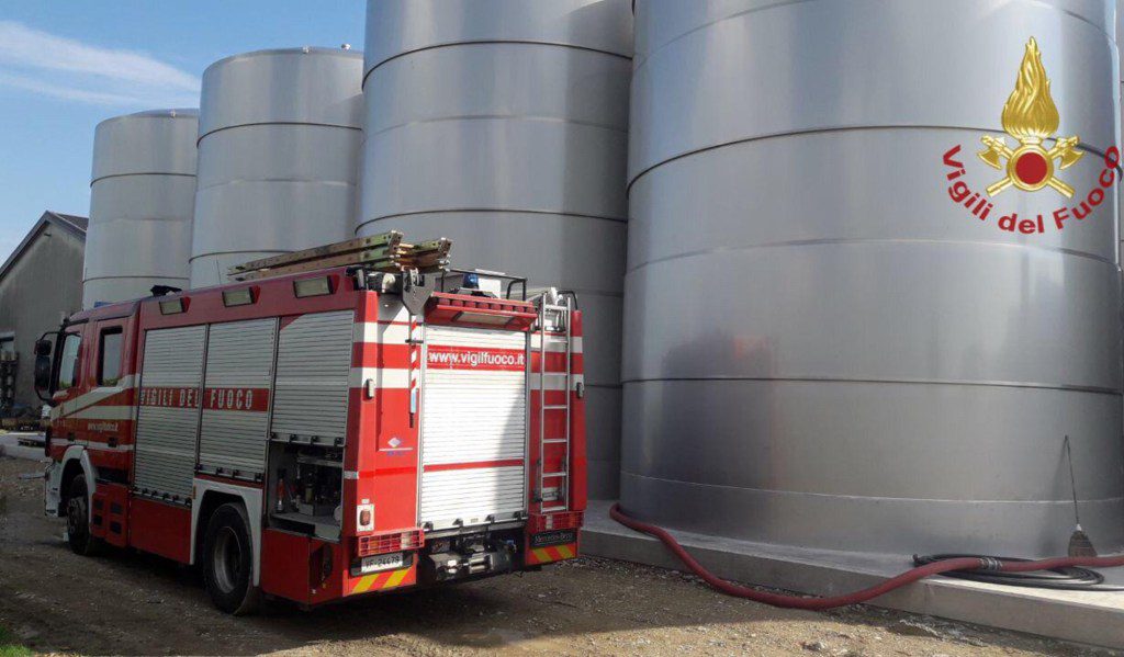 Un camión de bomberos está estacionado junto a una hilera de imponentes tinas de vino de acero inoxidable.