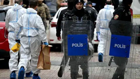 Getty Images Agentes de la policía forense turca cargan cajas mientras caminan frente a la Iglesia de Santa María después de un ataque, en Estambul, el 28 de enero de 2024.